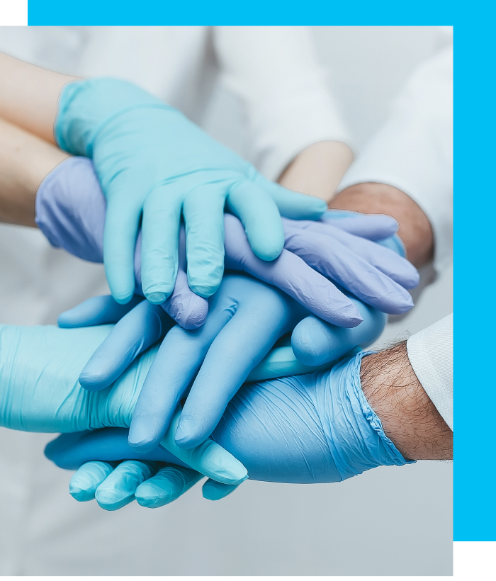 Close-up shot of a team of medical workers in blue gloves holding hands together.