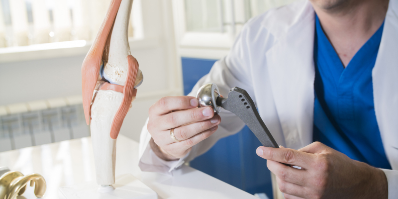 A doctor working on a model of a hip joint illustrates the tips to recover after a hip replacement surgery.