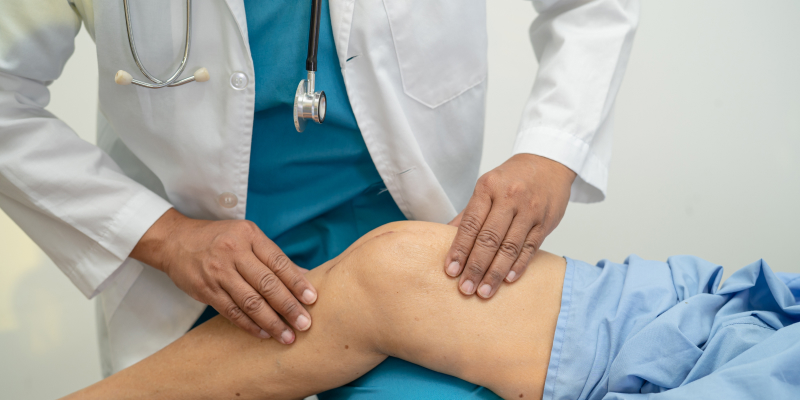 A close-up image of an orthopedist examining the knee of a senior patient illustrates overcoming the fear of knee replacement.
